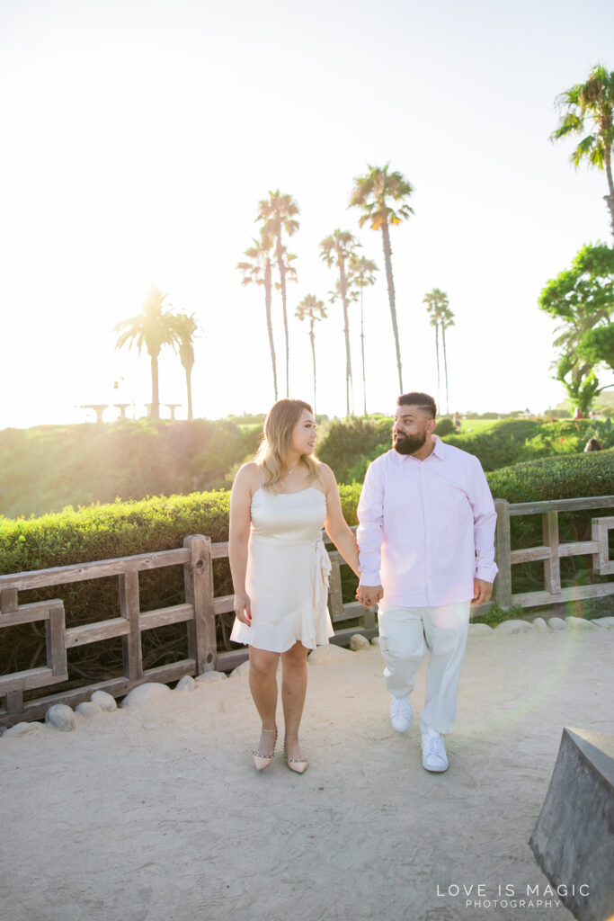 couple walks in glowy sunlight with palm trees in the background, photo by Love is Magic Photography