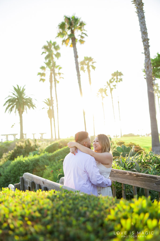 couple hugs in glowy sunlight with palm trees in the background, photo by Love is Magic Photography