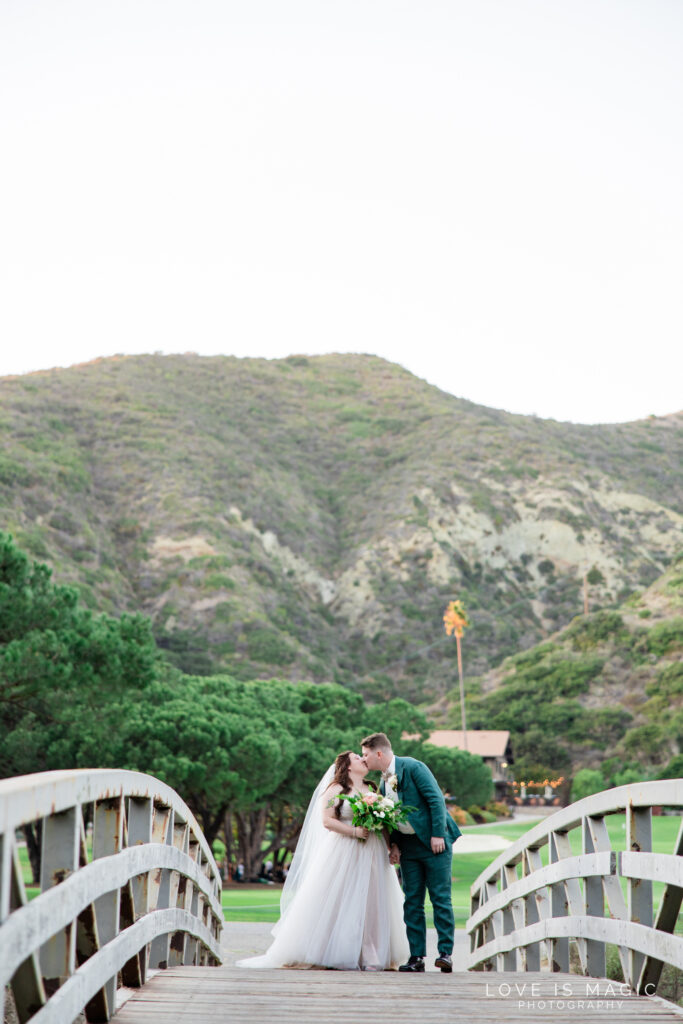 bride and groom kiss on bridge at The Ranch Laguna Beach, photo by Love is Magic Photography