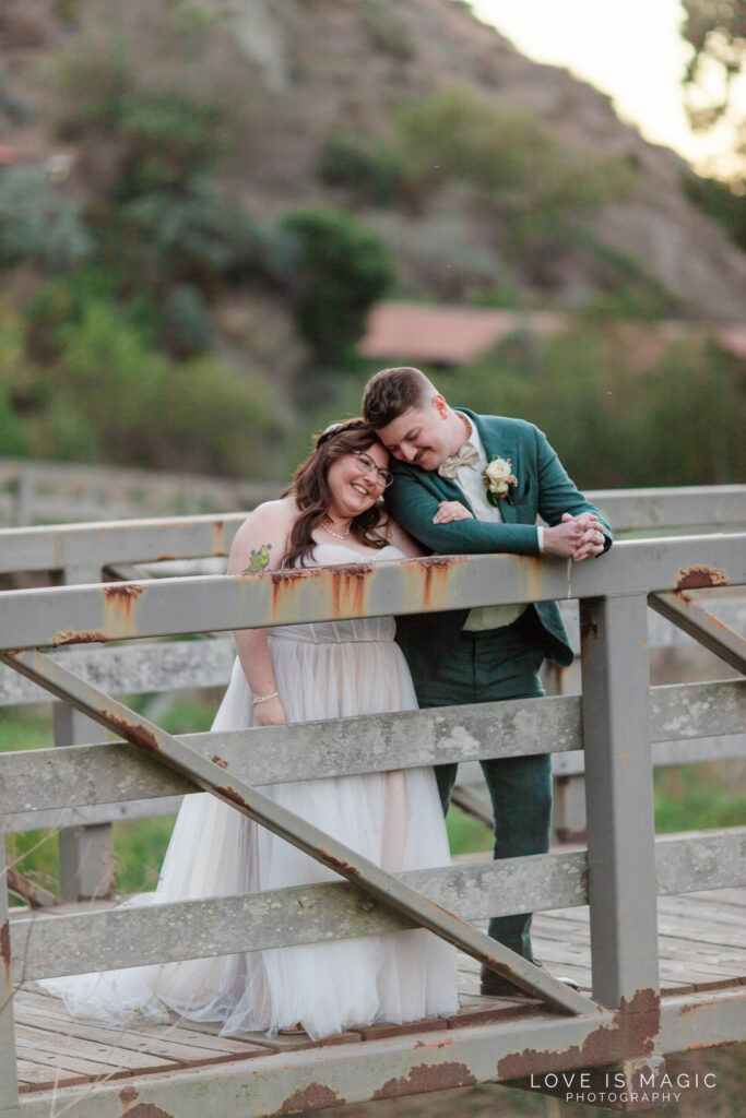 bride and groom snuggle on bridge at The Ranch Laguna Beach, photo by Love is Magic Photography