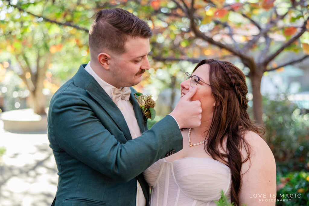 groom wipes tear from brides face, photo by Love is Magic Photography