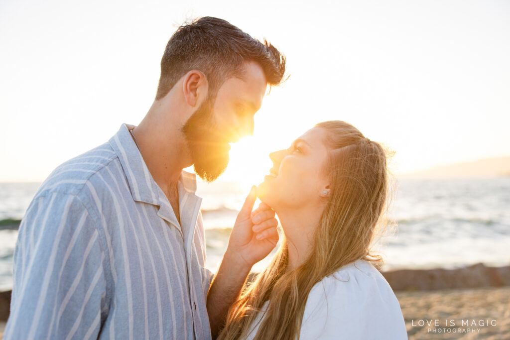 boy pulls girl in close for a kiss in the glowy sunset, photo by Love is Magic Photography