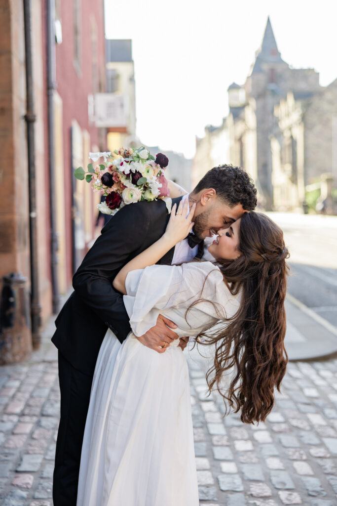 Newly married couple walking through Edinburgh Old Town at sunset