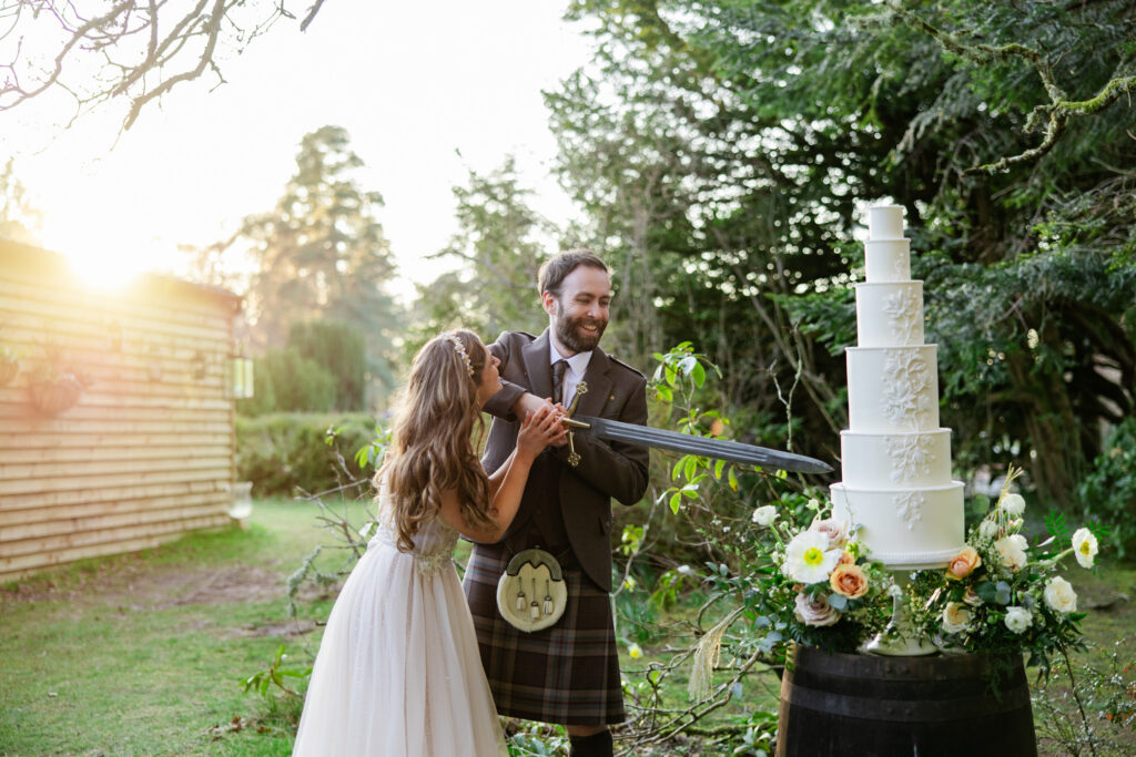 kilt wearing groom and bride cut cake with sword