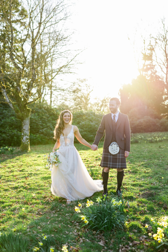 kilt wearing groom and bride laugh in sunlight