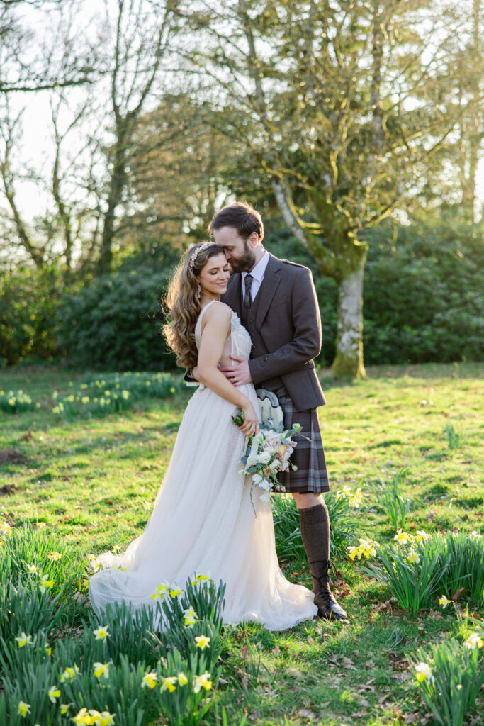 kilt wearing groom kisses brides cheek