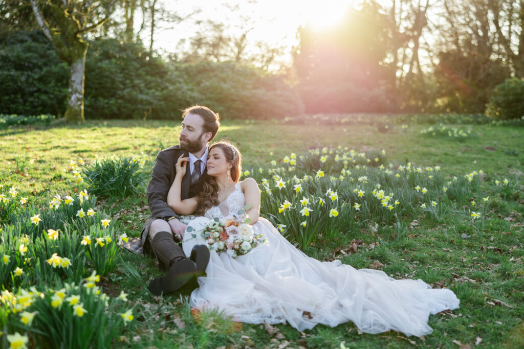 Glasgow wedding photographer captures kilt wearing groom embraces bride in field of daffodils