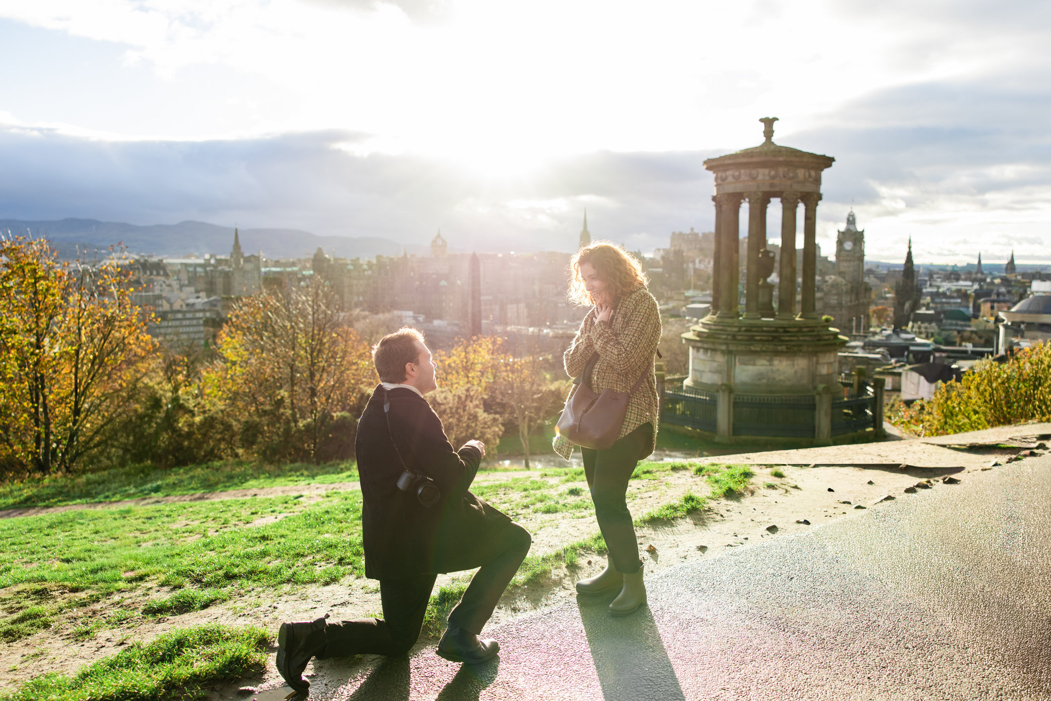 Surprise proposal on Calton Hill in Edinburgh with castle skyline at sunset