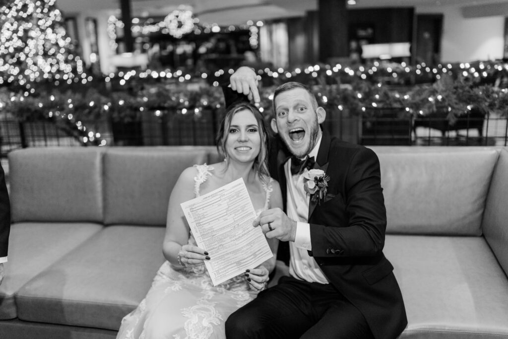 groom cheers and points to marriage certificate