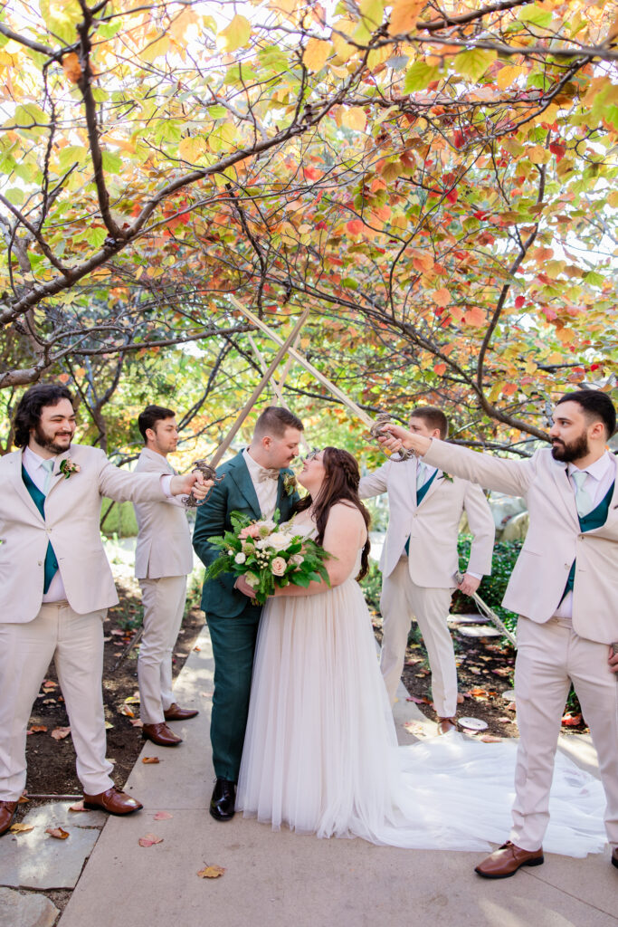 groomsmen hold swords over kissing  couple at lord of the rings inspired wedding