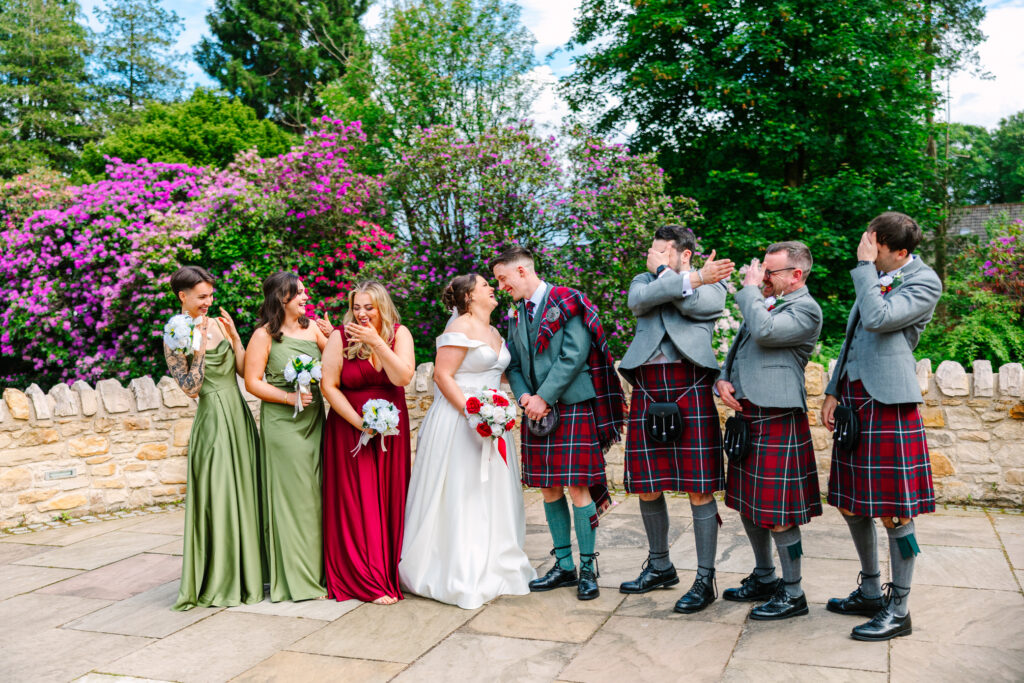 Bride, groom and wedding party laughing together during fun group portraits at Kilmardinny House