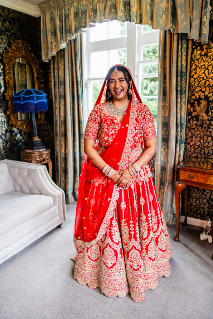 Bride smiling in a traditional red wedding dress at Melville Castle wedding venue
