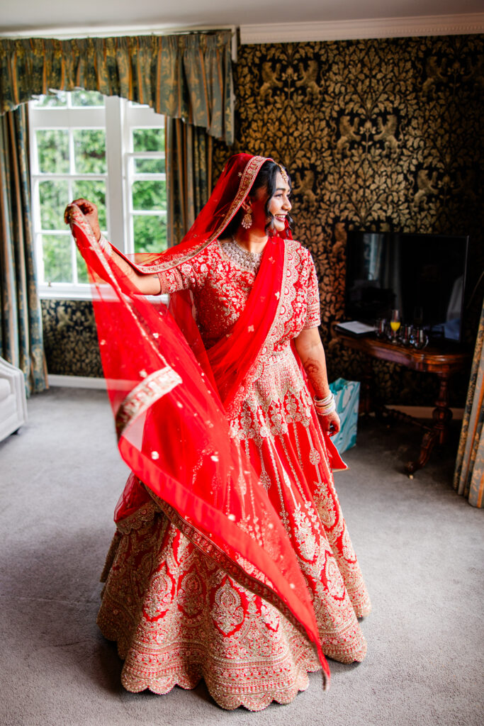 Bride twirling in a traditional red wedding outfit while getting ready at Melville Castle