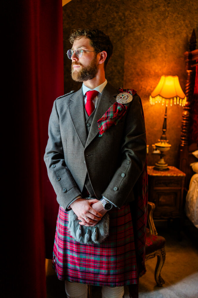 Groom wearing a Scottish kilt and tartan fly plaid before his Melville Castle wedding