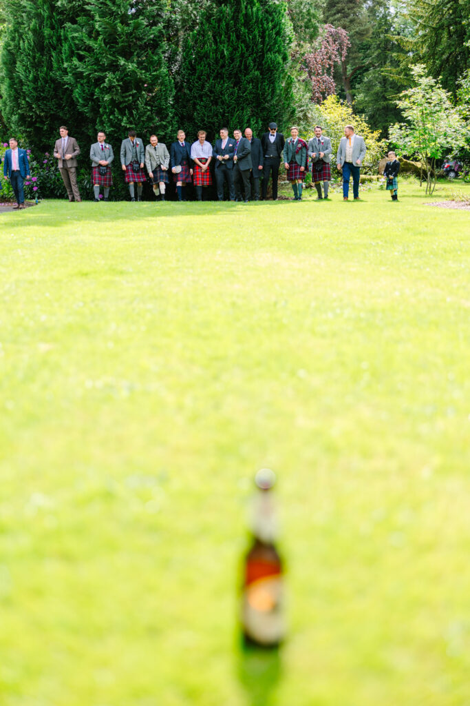 Guests preparing to throw boules during outdoor wedding games in the grounds of Kilmardinny House