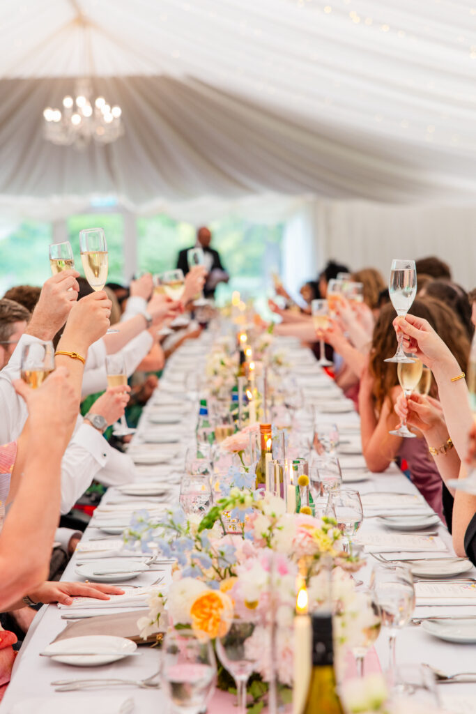 Guests raising champagne glasses for a wedding toast inside the Melville Castle marquee
