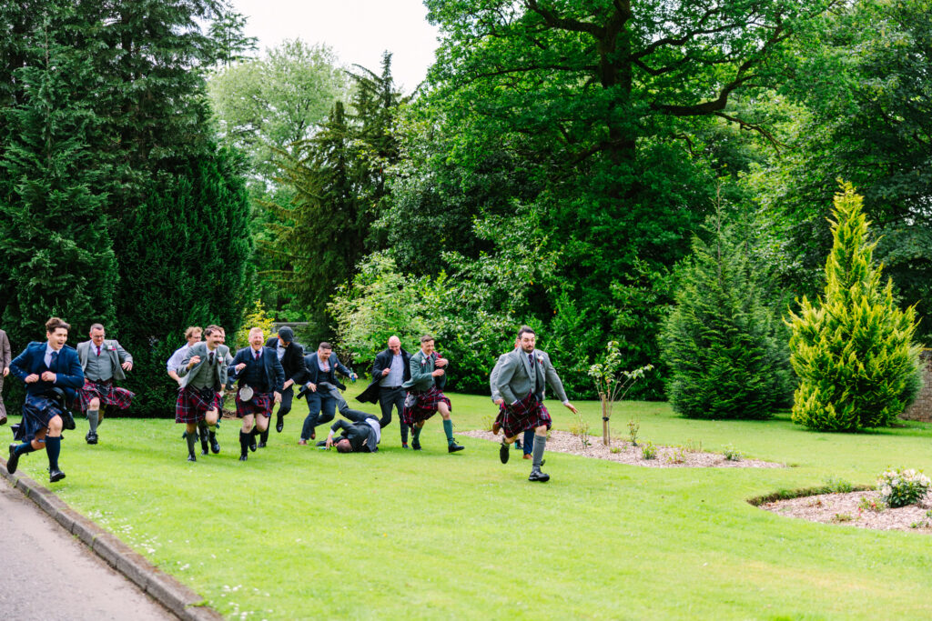 Guests sprinting across the gardens during lively wedding entertainment at Kilmardinny House