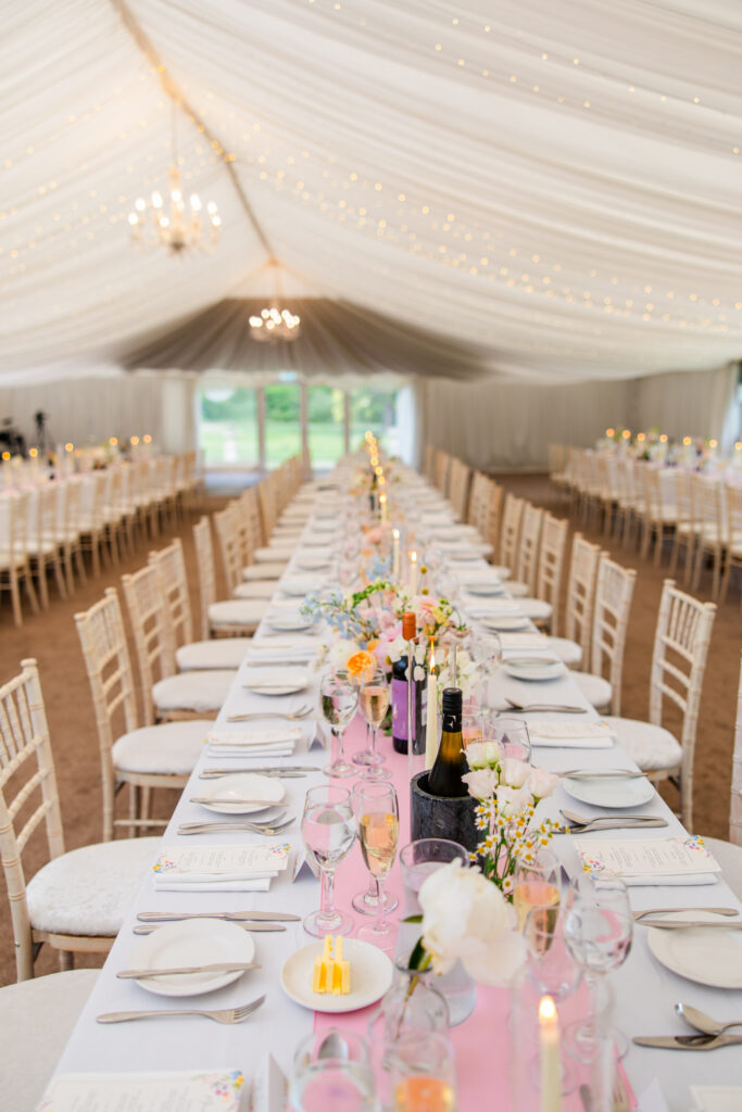 Long banquet table with pastel flowers and candles inside the Melville Castle wedding marquee