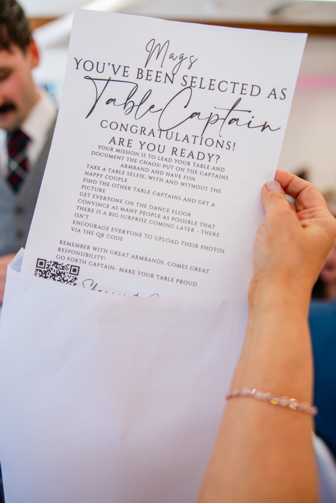 Wedding guest opening a fun table captain challenge card during the reception at Kilmardinny House