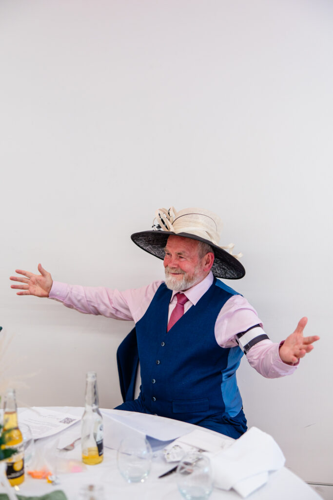 Wedding guest wearing a large fascinator and captain armband during a reception game at Kilmardinny House