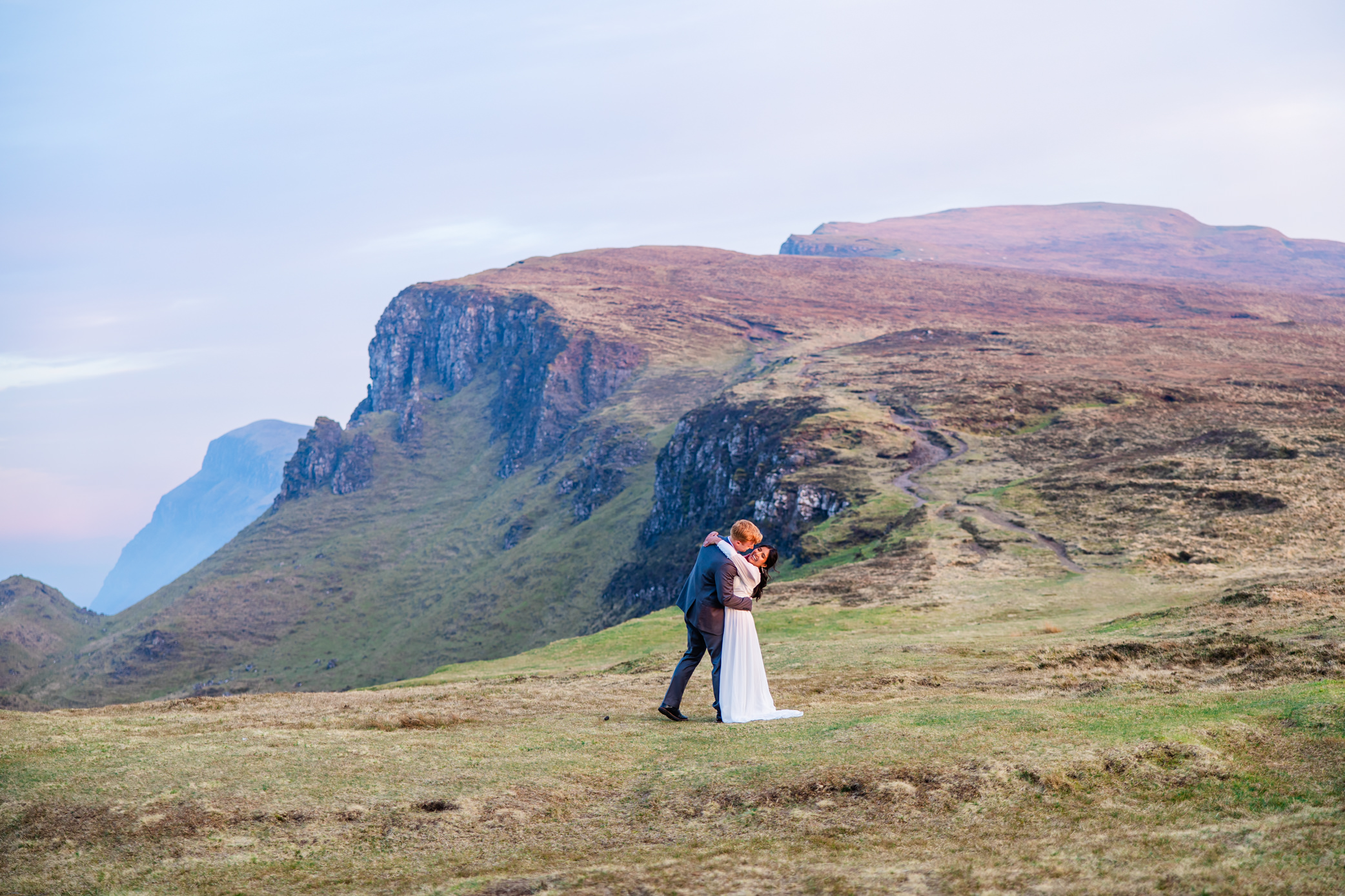 Bride and groom embracing in the dramatic Quiraing mountains during their Isle of Skye elopement