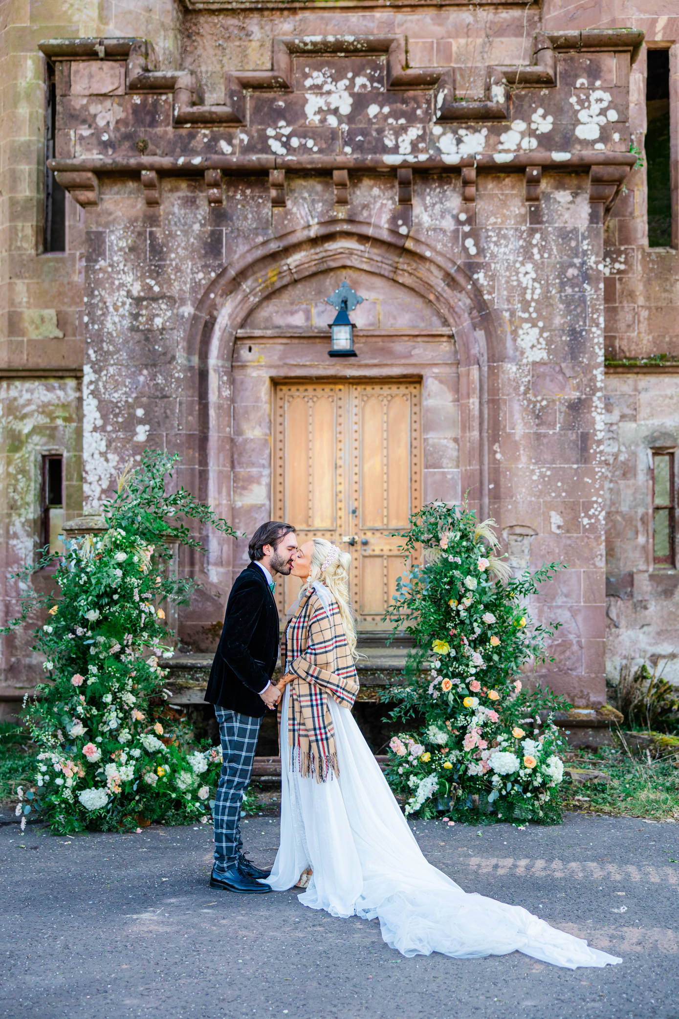 Bride and groom posing together beneath the ornate entrance of Culdees Castle