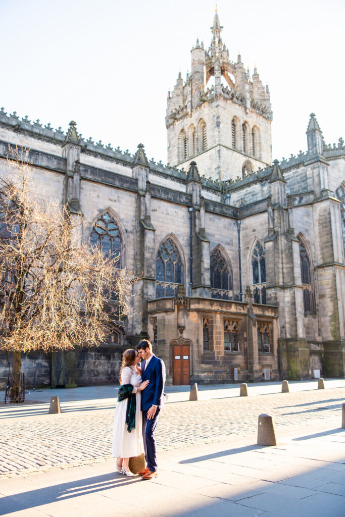 Bride and groom walking together outside a historic Edinburgh church during their wedding day