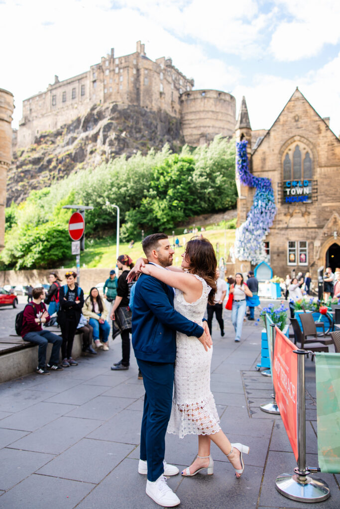 Couple embracing outside Cold Town House in Edinburgh’s Old Town, with Edinburgh Castle visible behind them