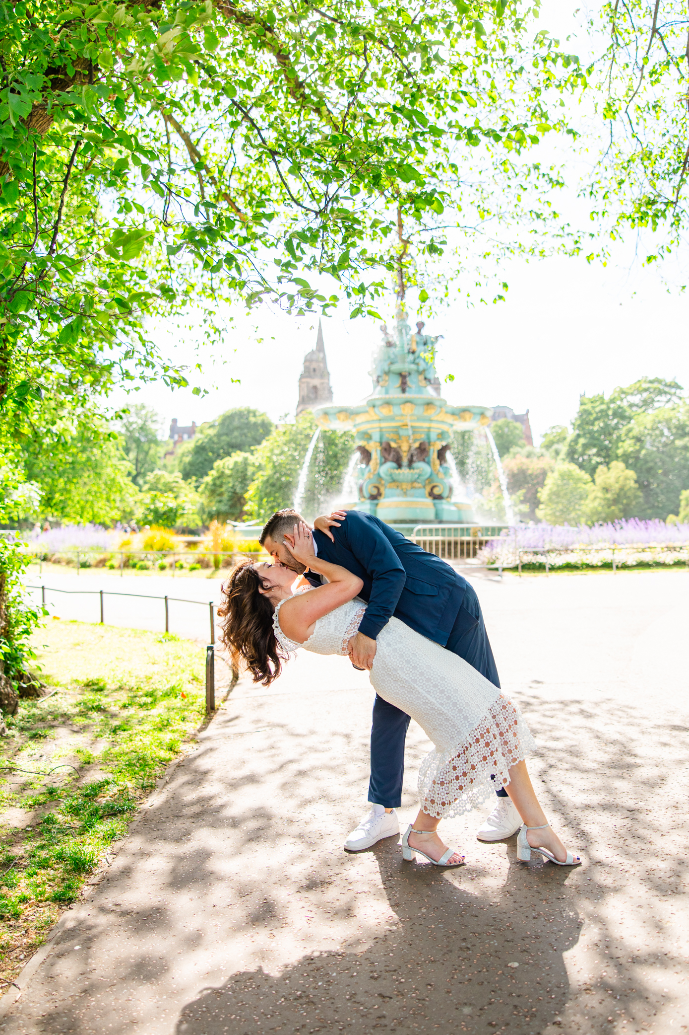 Engaged couple sharing a romantic dip kiss in front of Ross Fountain in Edinburgh