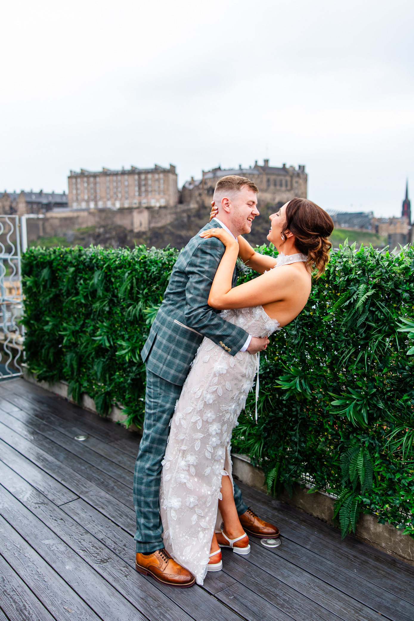 Newlywed couple embracing on Skybar rooftop terrace overlooking Edinburgh Castle