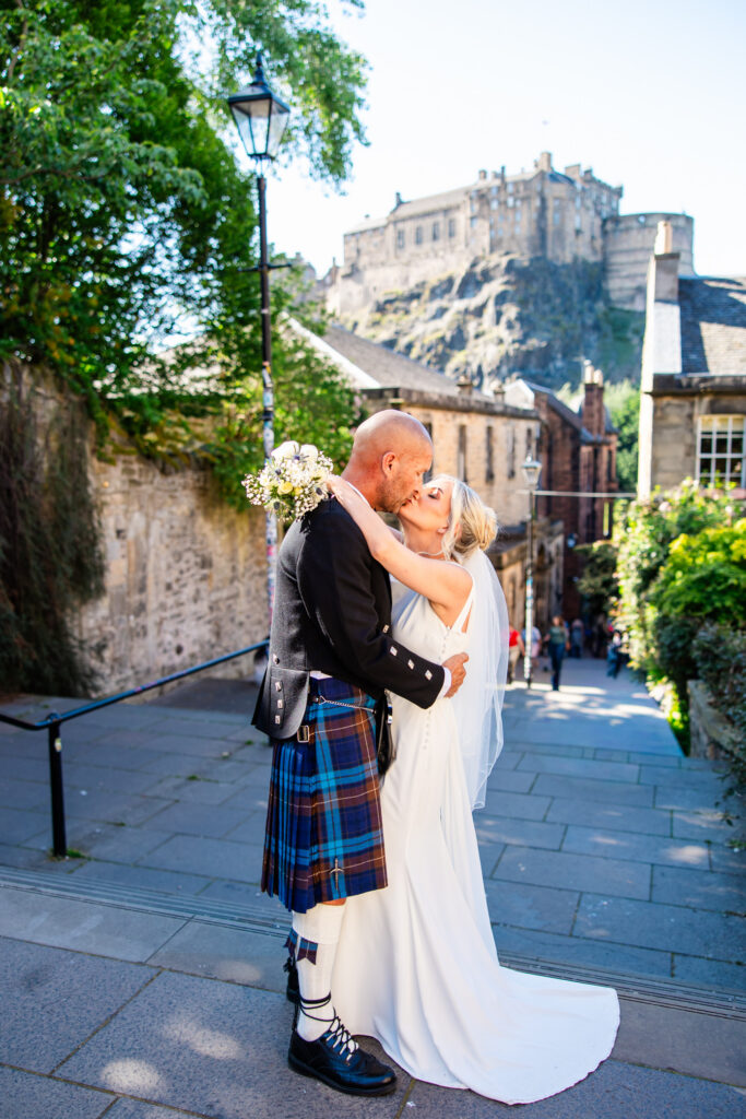Newlyweds embracing beside historic buildings in Edinburgh Old Town