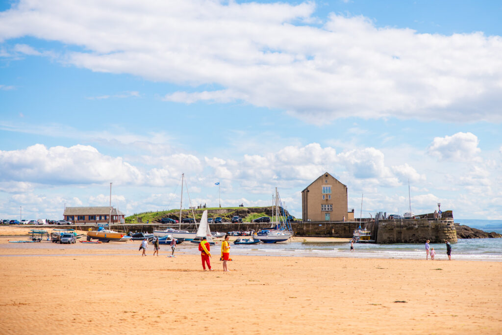 Wide view of Elie beach and harbour with the Fife coastline under a blue sky